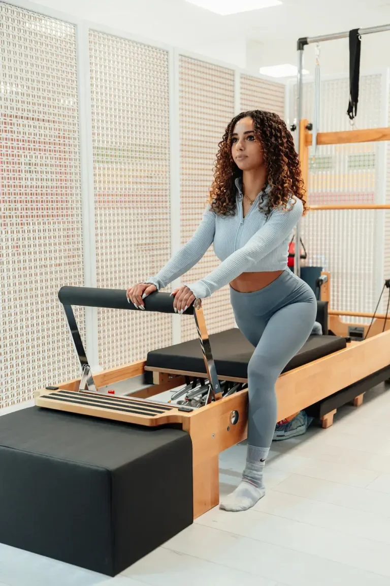Woman performing lunge exercise on a Pilates Reformer machine in a studio.